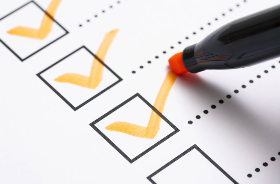 A checklist being ticked off with orange check marks and a black marker, representing model evaluation
